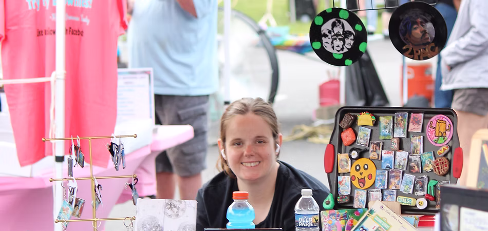 young lady sitting at a vendor booth in the vendor area at the Goochland day festival